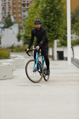 A cyclist in black sportswear on a blue gravel bike.