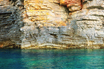 Sharp cut cliff and the tranquil turquoise sea water - obrazy, fototapety, plakaty