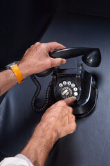  hands dial a phone number on a vintage rotary telephone