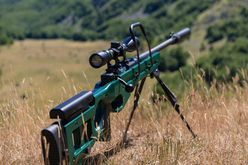 A green military sniper rifle with a scope for long distance tactical modern warfare in yellow...