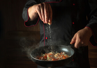 The cook adds salt to a steaming hot pan. Menu idea for a hotel with advertising space. Asian national cuisine. Restaurant menu or recipe. Copy space