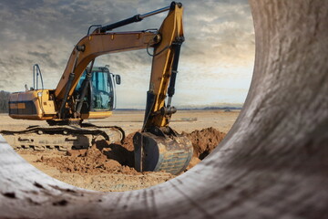 A powerful caterpillar excavator digs the ground against the blue sky. Earthworks with heavy...