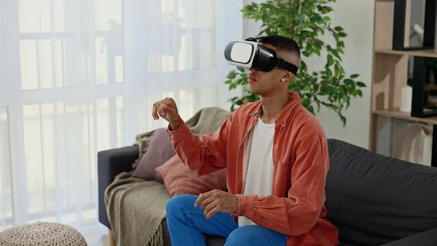 African american man use vr headset glasses at home for studying purposes moving hands in air, sitting in living room. Virtual reality and modern gadget device