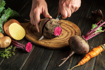 Close-up of a cook hands with a knife. Slicing beets or beta vulgaris by the hands of a chef on a cutting board for cooking diet food in the kitchen