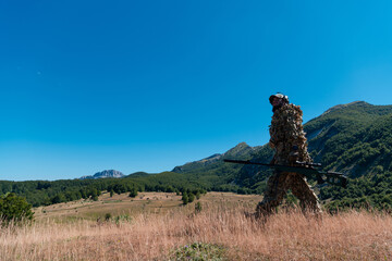 Army soldier holding a sniper rifle with scope and walking in the forest. war, army, technology and...
