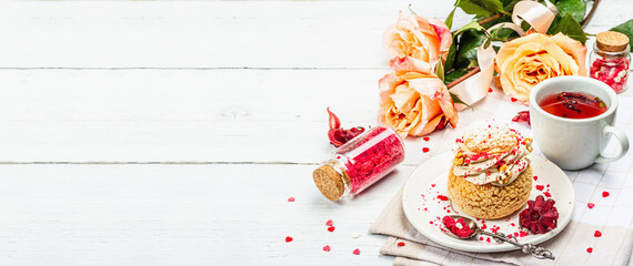 The concept of romantic tea. French Shu cake, hibiscus tea, bouquet of roses, festive decor