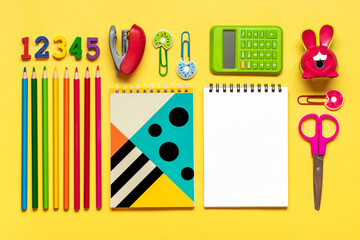 Stationary, back to school,summer time, creativity and education concept. Supplies - scissors, pencils, paper clips, note, stapler, calculator, notepad on yellow background, flatlay Mock up Top view