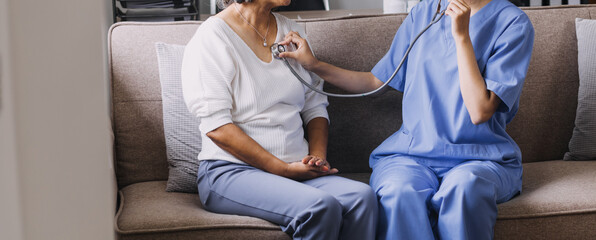 Obraz premium Homecare nursing service and elderly people cardiology healthcare. Close up of young hispanic female doctor nurse check mature caucasian man patient heartbeat using stethoscope during visit