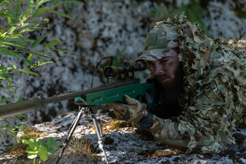 Army soldier holding sniper rifle with scope and aiming in forest. War, army, technology and people concept