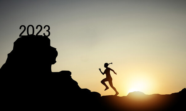 Silhouette of a young woman running with the numbers 2023 on the mountain at sunset with morning sunlight in the background.