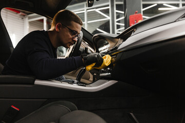 A man cleans a car and dries the interior with a microfiber cloth Manual car cleaning. Car...