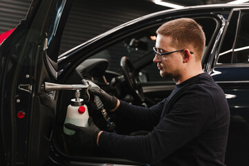 A man cleans a car and dries the interior with a dry cleaning gun. Manual car cleaning. Car...