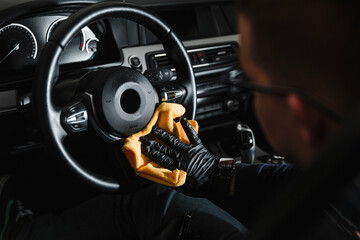 A man cleans a car and dries the interior with a microfiber cloth Manual car cleaning. Car detailing and car wash concept.