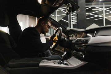 A man cleans a car and dries the interior with a microfiber cloth Manual car cleaning. Car detailing and car wash concept.