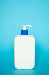 White unbranded bottle with a dispenser isolated on blue background. cosmetic packaging mockup with copy space. Bottle for a shower, gel, soap.