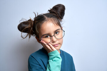 Little caucasian girl with suffering face expression holds cheek with hand, touching mouth with...