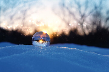 magic clear quartz ball on snow, winter natural blurred evening background. christmas, new year...