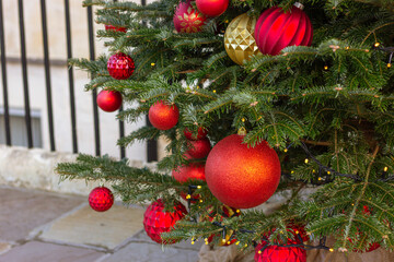 textured red and gold color ornates on Christmas tree. New Year, street festive decor