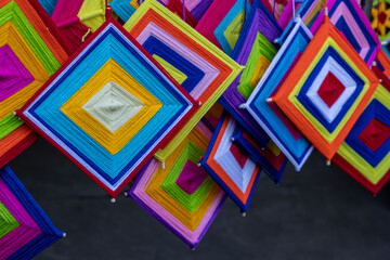 Close-up view of a set of hand-knitted yarn mobiles in a variety of colorful squares hanging.