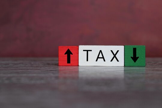 Wooden cubes with text TAX, downward and upward arrow. Tax rate increasing and decreasing concept