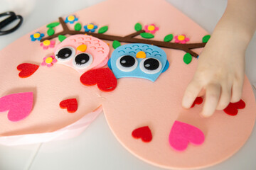 Obraz na płótnie Canvas A blogger girl makes a felt craft for Valentine's Day in the shape of a heart. The concept of children's creativity and handmade.