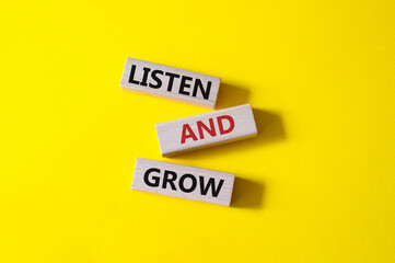 Listen and grow symbol. Concept words Listen and grow on wooden blocks. Beautiful yellow background. Businessman hand. Business and Listen and grow concept. Copy space.