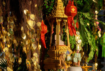 Thai Buddha altar, offerings, lanterns, golden leaves of Bodhi tree. 