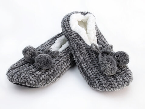 Home winter women's slippers on a white background. pair of fluffy fleece house shoe with pompoms. Gray rag soft closed slippers