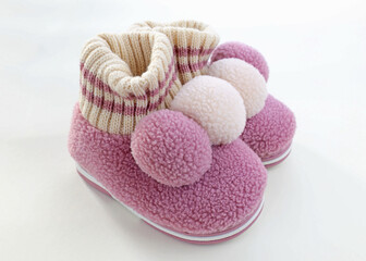 Woolen house children's slippers with balabon. Pink warm slippers for girls. A pair of child's shoes for cold weather on a white background.