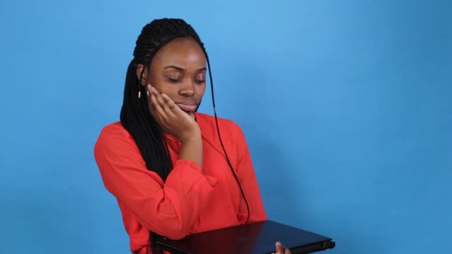 african american girl closes laptop after hard work on blue background.