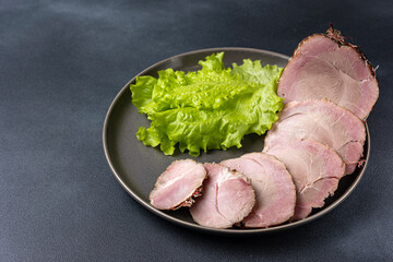 Traditional Ukrainian meat delicacies, snacks. Cold boiled pork on a dark table