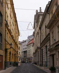 Fototapeta na wymiar Outdoor Christmas street decorations, trees with fairy lights between old historical buildings 