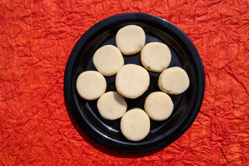 Indian sweet dish item Malai Peda made of mawa or khoya or Milk solids and sugar. Festival special traditional Indian and Pakistani mithai Malai penda or Doodh peda or milk peda on orange background
