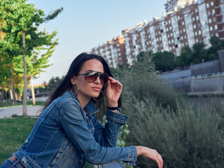 Girl with sunglasses looking at the city. Girl with long and brown hair. Woman wearing sunglasses.
