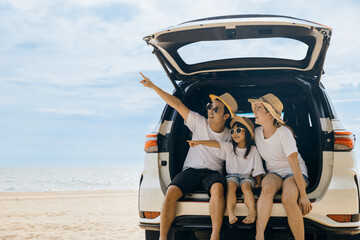 Family Day. Father, Mother and daughter enjoying road trip sitting on back car and point finger out blue sky, Happy people having fun in summer vacation on beach, Family travel in holiday at sea beach