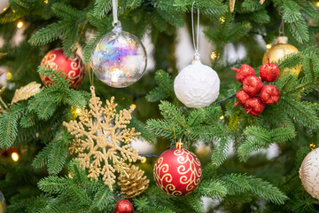 Christmas tree and Christmas decorations. Beautifully decorated Christmas tree on a blurred background, close-up of balls on the Christmas tree, bokeh garlands in the background, New Year. 2023.