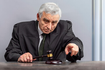 Judge banging judge's gavel, index finger pointing. Law Lord wearing gown using a hammer for...
