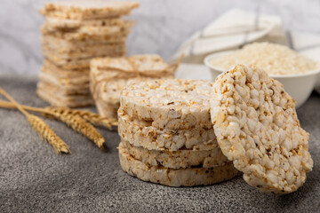 Rice cakes on a black texture table, against the background of a plate of rice. Close-up. Healthy food. Diet food.