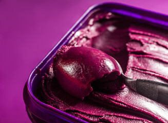 Closeup on creamy acaí pot over purple surface, traditional brazilian food.