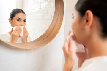 Young woman cleaning removing makeup on her face in bathroom at home , beauty wellness concept