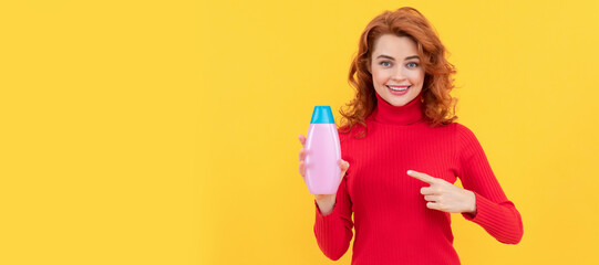 girl curly hair pointing finger on shampoo bottle. hair conditioner advertisement.