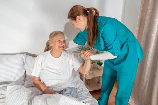 Nurse helping an elderly woman at her home. Solicitous professional medical female staff caring in a geriatric institution with a senior patient. Lifestyle