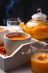 A teapot and two cups with home made sea-buckthorn tea with berries, seasonal tea time concept.
