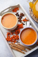 Two cups with home made sea-buckthorn tea with berries and spices on white tray, seasonal tea time concept.