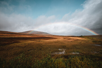 Landscape in northern Norway on a moody autumn day with a rainbow background