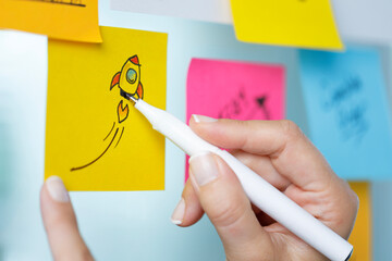 Business woman writing on colorful sticky note paper. Highlights the start up projects