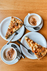 Delicious pie with a cup of coffee close-up. Tasty breakfast. A piece of cake on a plate, a white cup on a wooden background. View from above