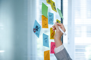 Business woman writing on colorful sticky note paper. Highlights the motivation text. Making the workflow plan