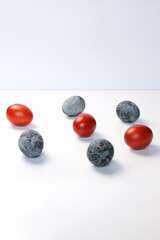 Defocus blue and red eggs on white background. Minimal Easter celebration concept. Design, visual art, minimalism. Balance and harmony concept. Mental health. Pattern. Vertical. Out of focus