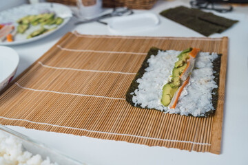 Sheet of stuffed nori seaweed ready to make homemade sushi on the family kitchen table.